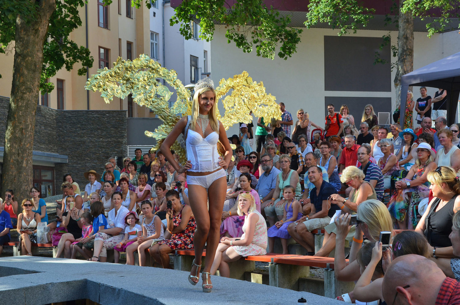 Modelka procházející po přehlídkovém molu na letní scéně Eurocentra v Jablonci nad Nisou ve spodním prádle a luxusní bižuterii v podobě korunky, náhrdelníku a andělských křídel na veletrhu skla a bižuterie Křehká krása