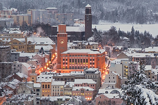 Zimní Jablonec nad Nisou večer – zasněžená rozsvícená radnice v pozadí s kostelem Nejsvětějšího Srdce Páně a přehradou