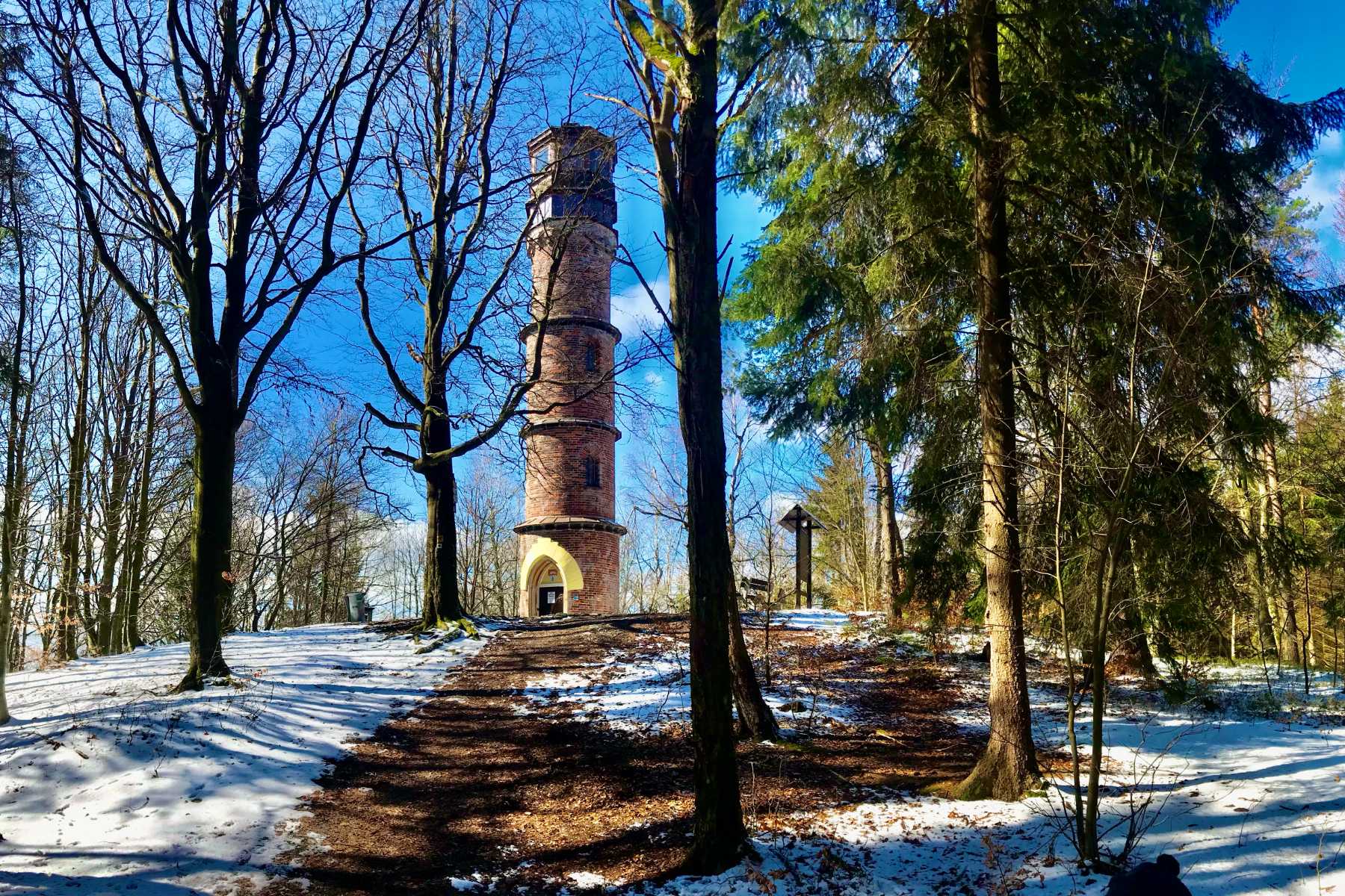 Kamenná rozhledna Kopanina obklopená stromy na konci zimy- Jablonecko
