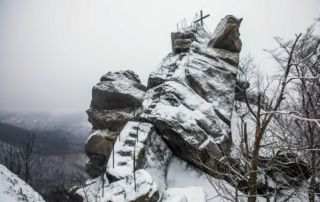 Vyhlídka Ořešník v zimě – skalní dominanta nad Hejnicemi, Jizerské hory. Pohled na skálu se strmými schody a křížem