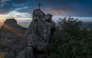 Západ slunce na vyhlídce Ořešník – skalní dominanta nad Hejnicemi, Jizerské hory. Pohled na skálu se strmými schody a křížem