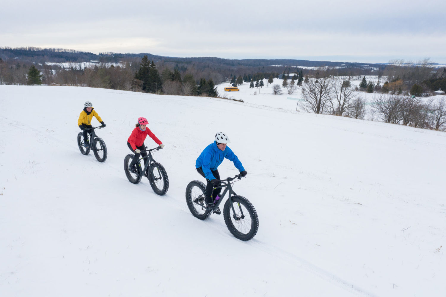 Tři cyklisté jedoucí zimní krajinou na speciálních kolech fatbike - Jizerské hory