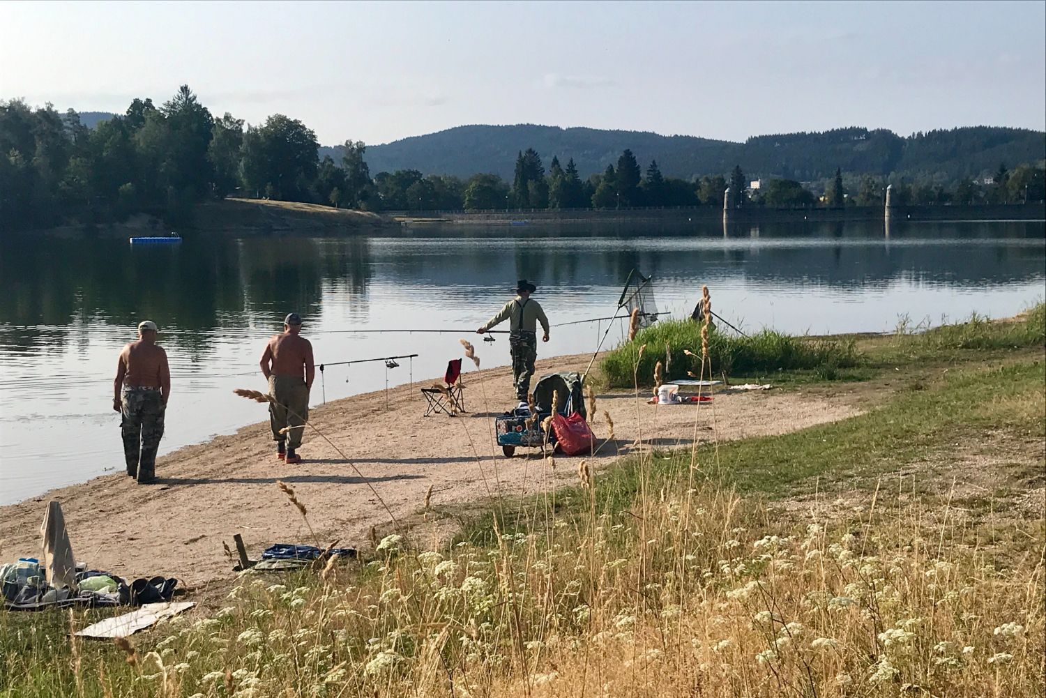 Skupinka rybářů na břehu jablonecké přehrady s rybářským náčiním.