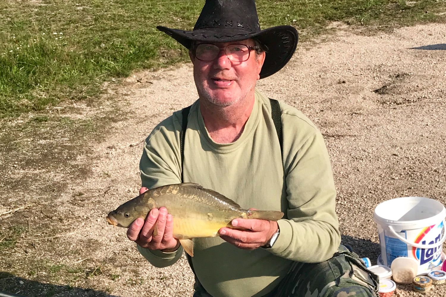 Rybář držící v ruce kapra uloveného v jablonecké přehradě.