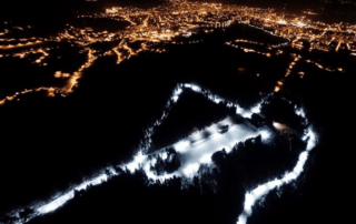 Letecký večerní snímek svítícího běžkařského areálu Kolečko – Jablonec nad Nisou Břízky v zimě